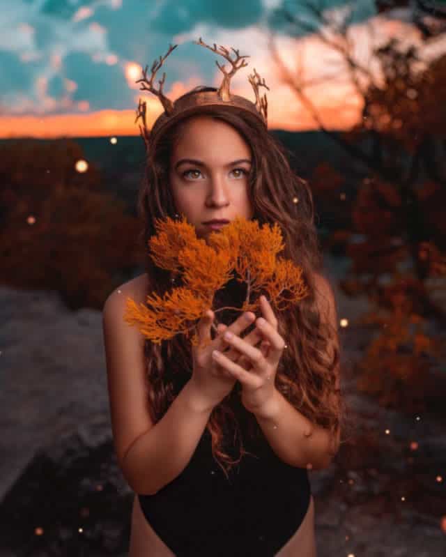 Girl holding an orange branch in a magical forest.